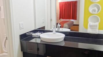 A modern bathroom with a black countertop, white sink, and a mirror.