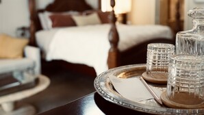 A hotel room with a neatly made bed, a bedside table with a tray containing glasses and a decanter, and a view of the room's interior. - Blue Ridge Inn Bed & Breakfast (Blue Ridge)