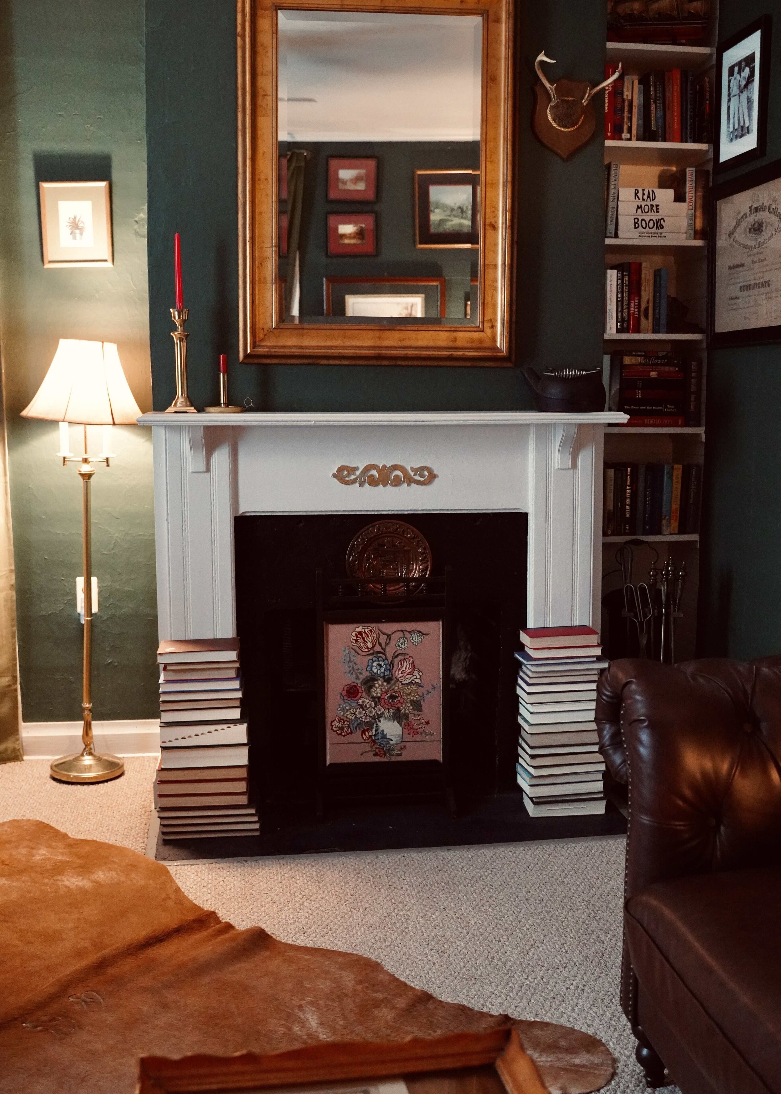 Un salon avec une cheminée, des étagères à livres, un miroir et une lampe.
