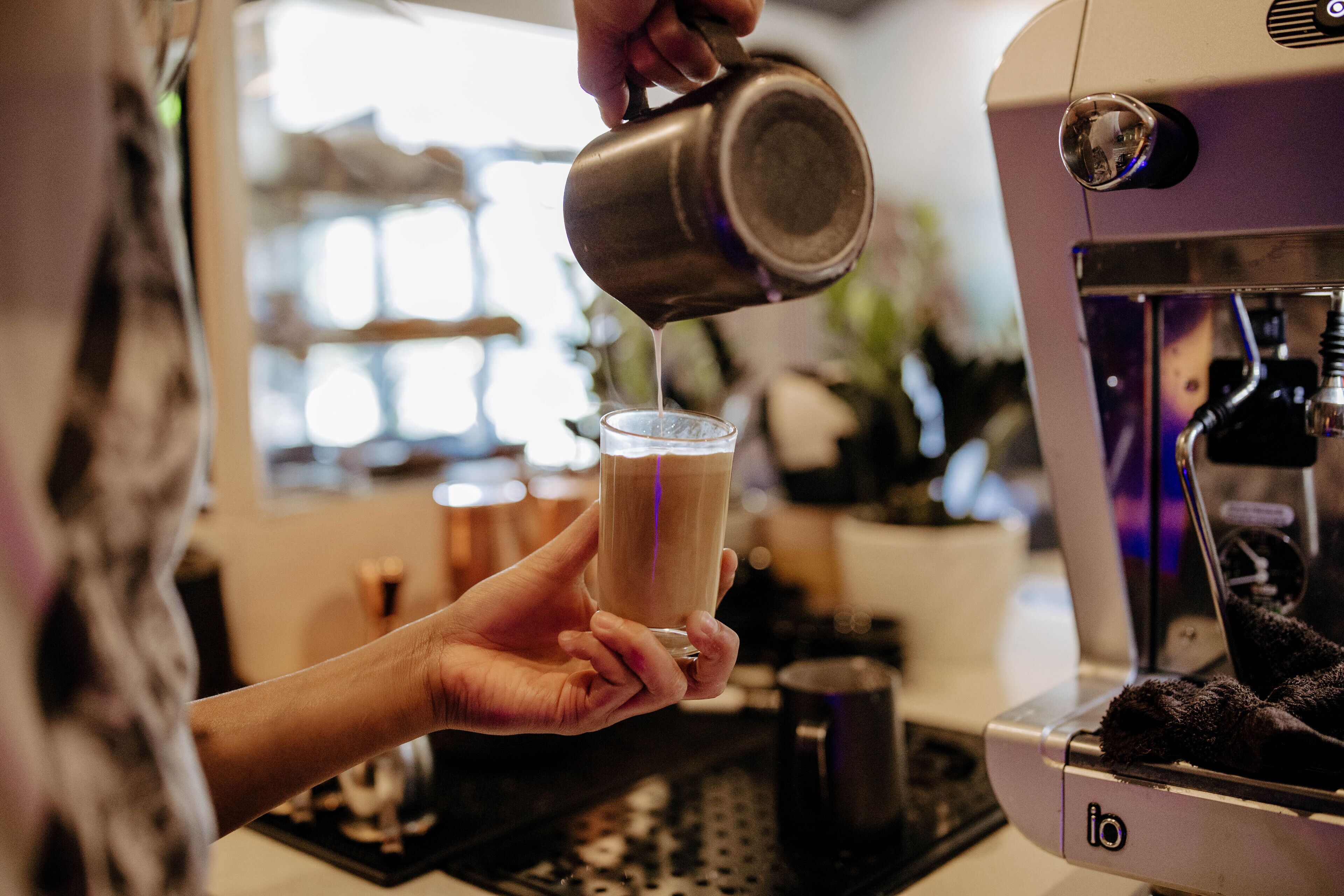 Una persona sirve una bebida desde una taza de metal a un vaso.