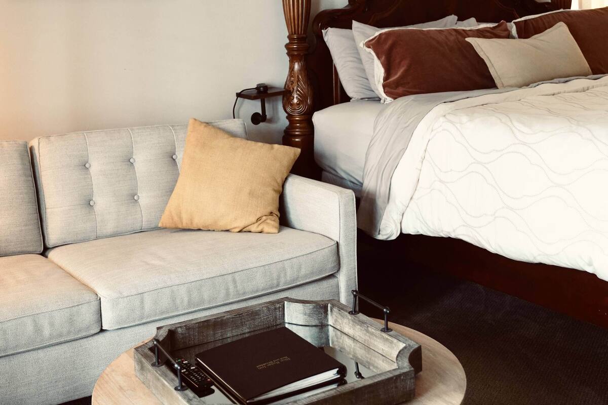 Quarto de hotel com uma cama, um sofá e duas fotos emolduradas na parede.