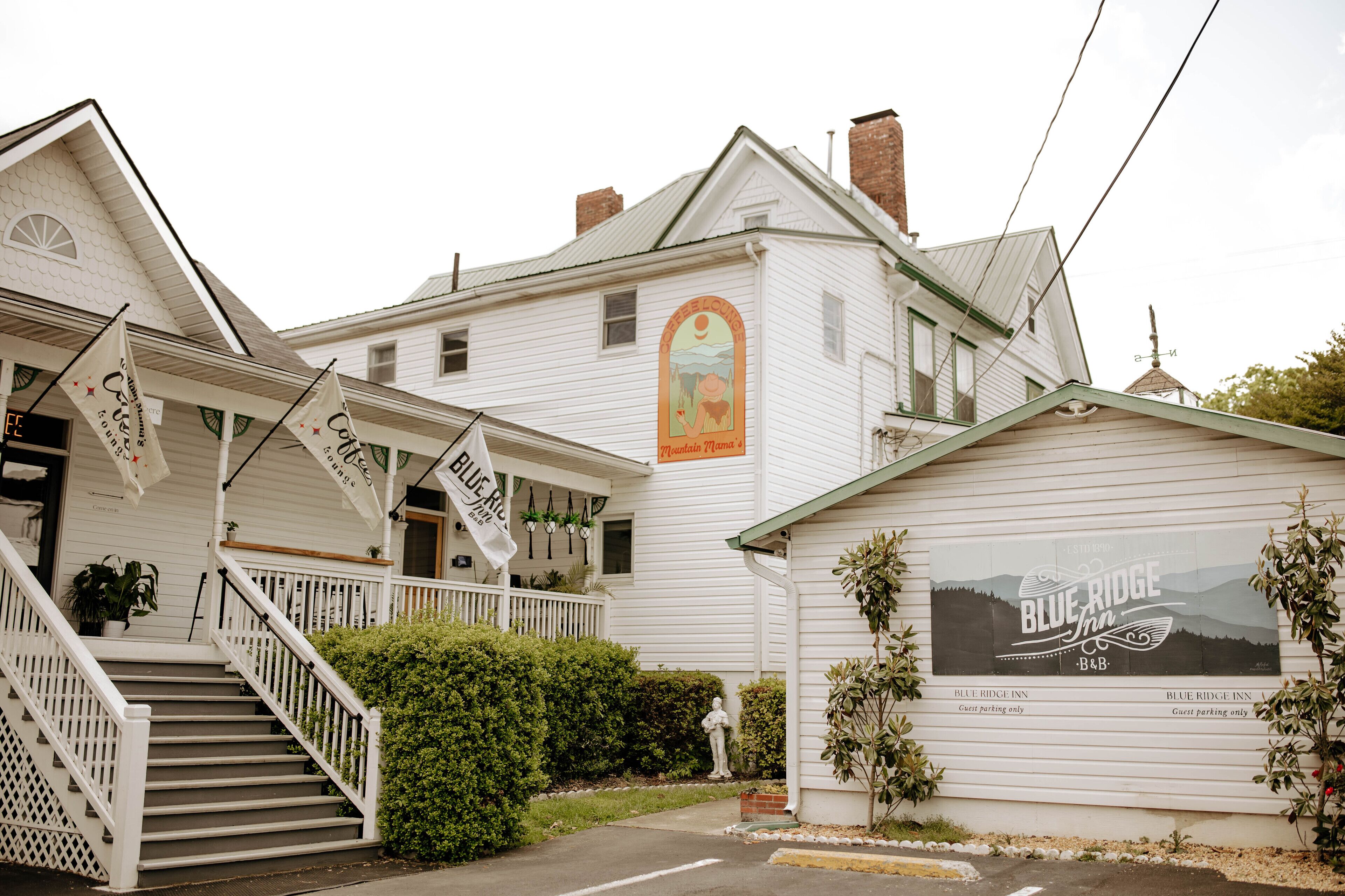 A white building with a sign for Blue Ridge Inn. There are stairs leading to a porch, and a statue in front.