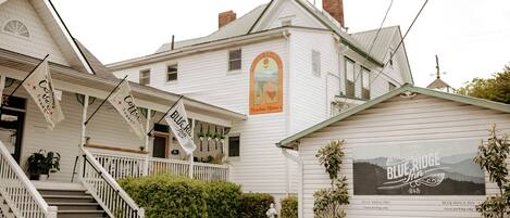 A white building with a sign for Blue Ridge Inn. There are stairs leading to a porch, and a statue in front.