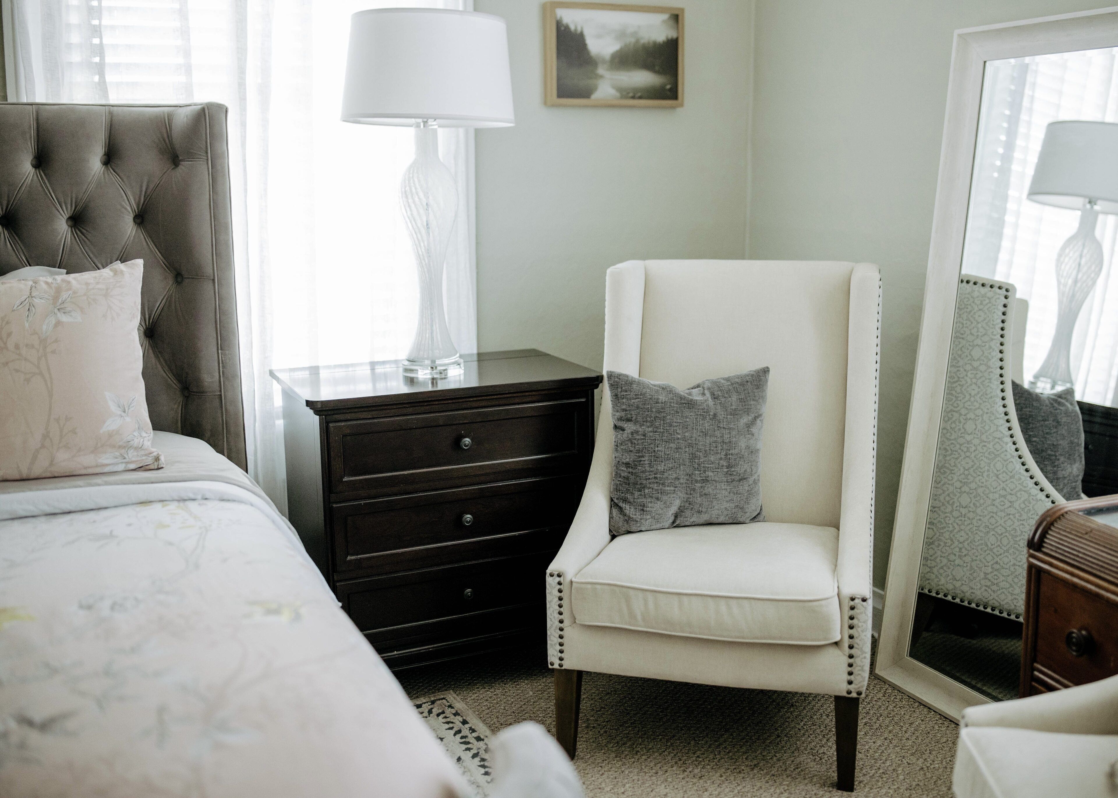A bedroom with a bed, a nightstand, a chair, and a dresser.