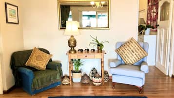A room with a blue armchair, a green armchair, a wooden console table with a lamp, and a mirror on the wall.