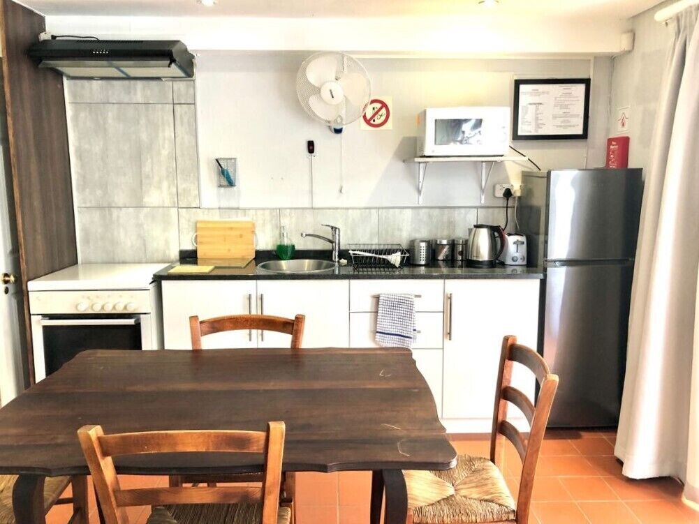 Une cuisine compacte comprenant une table à manger, des chaises, un four à micro-ondes, un réfrigérateur et une cuisinière.