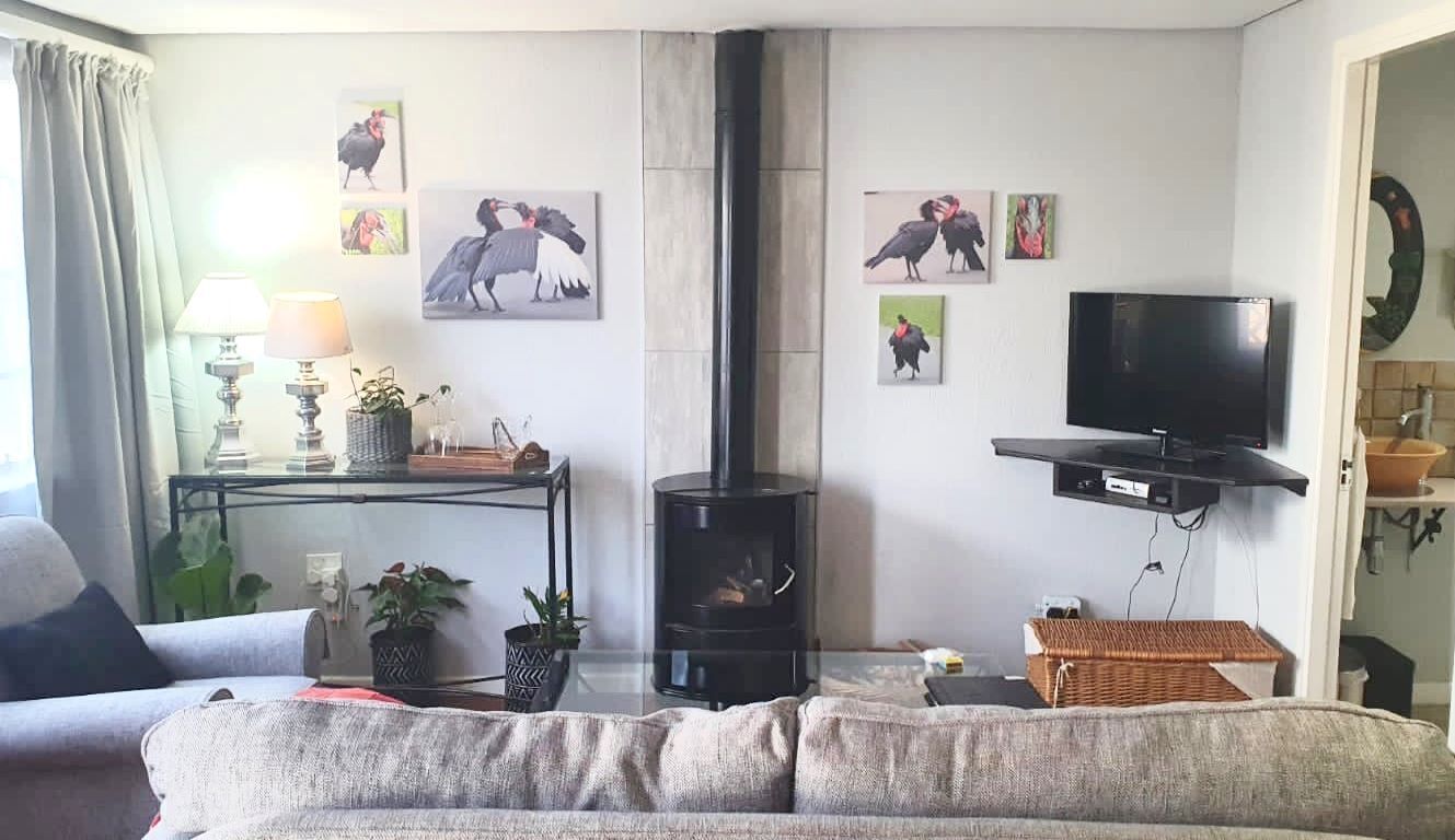 A living room with a sofa, a TV, a fireplace, and wall art.