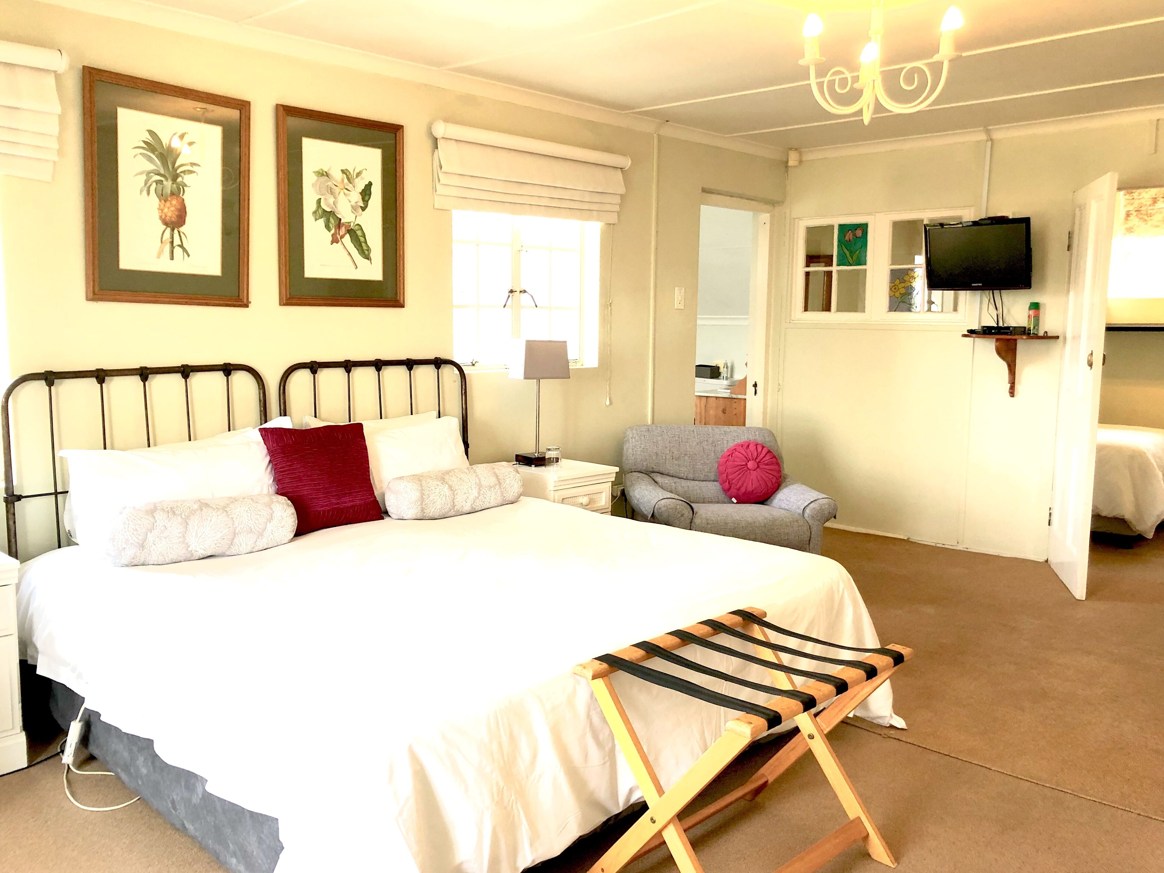 A neatly arranged bedroom with a bed, a chair, a TV, and a small table.