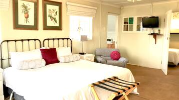 A neatly arranged bedroom with a bed, a chair, a TV, and a small table.