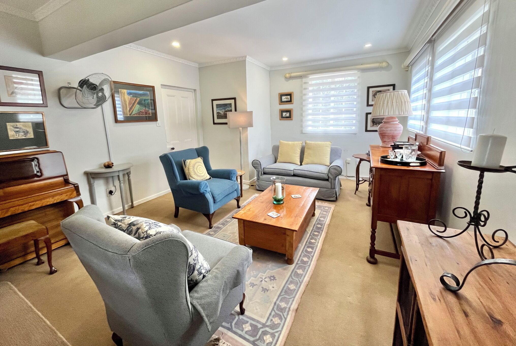 Een woonkamer met een piano, twee banken, een salontafel en een lamp.