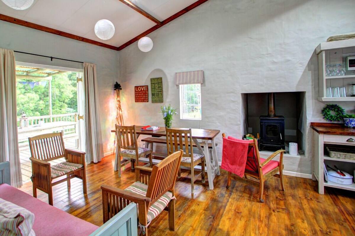 A cozy room with a wooden dining table, chairs, a fireplace, and a view of the outdoors.