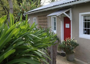 A small building with a red door, a window, and a metal roof. - Oakhurst Farm Cottages (Wilderness)