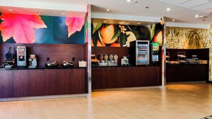 A hotel reception area with a counter, a coffee machine, and a fruit display. - Fairfield Inn & Suites by Marriott Snyder (Snyder)