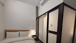 Een hotelkamer met een bed, nachtkastje, lamp en een kledingkast.