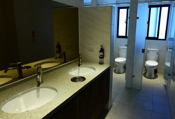 Un baño moderno con dos lavamanos, un espejo grande y un inodoro.