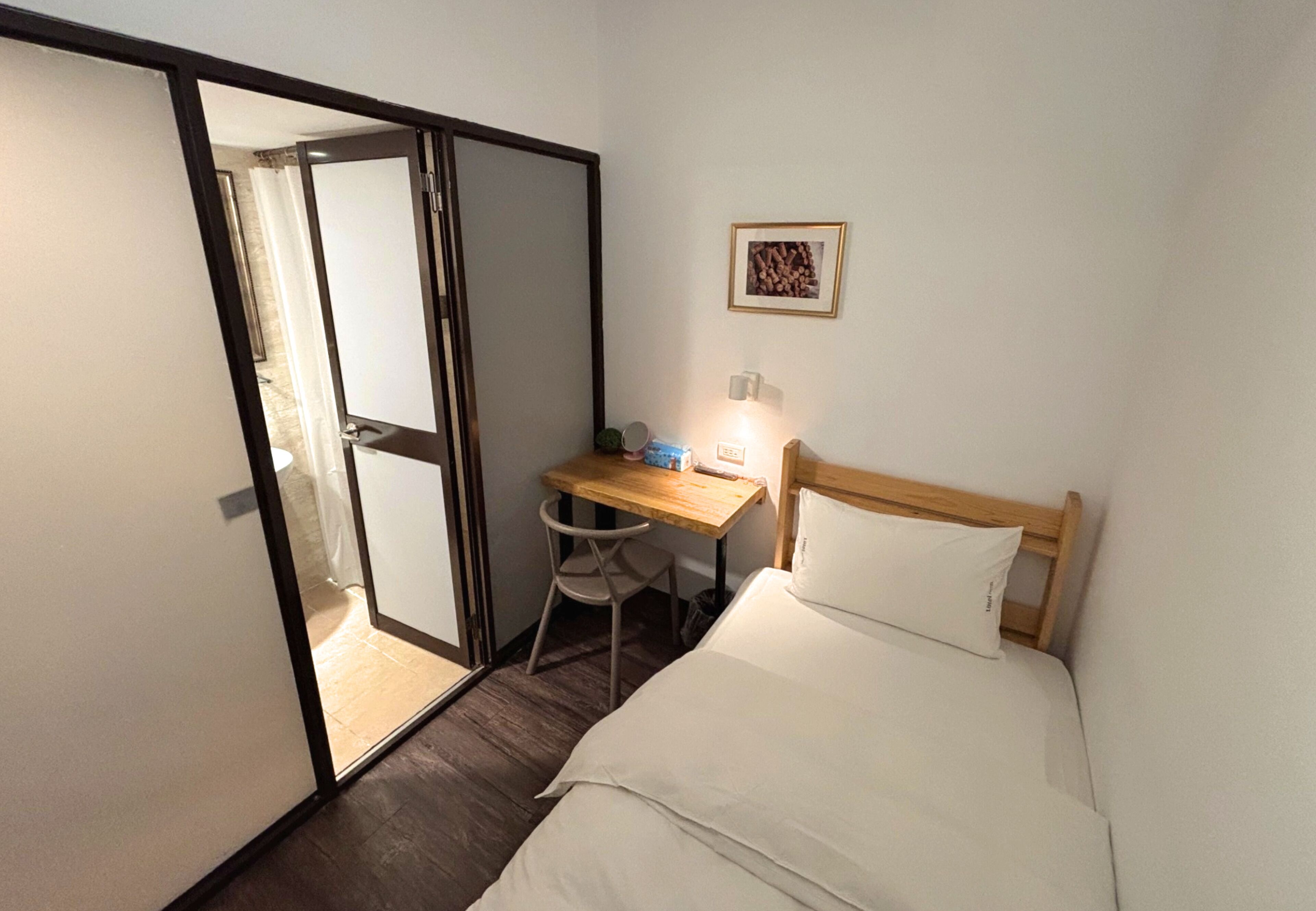 A bedroom with a bed, a desk, and a chair.