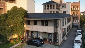Een hotel met modern design, met een plat dak, grote ramen en een parkeerplaats met meerdere auto's.