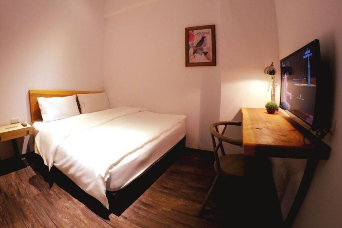 Une chambre d’hôtel comprenant un lit, un bureau avec une chaise, une télévision et une petite plante.