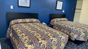 A hotel room with two beds, each with patterned bedding, a large headboard, and framed artwork on the walls.