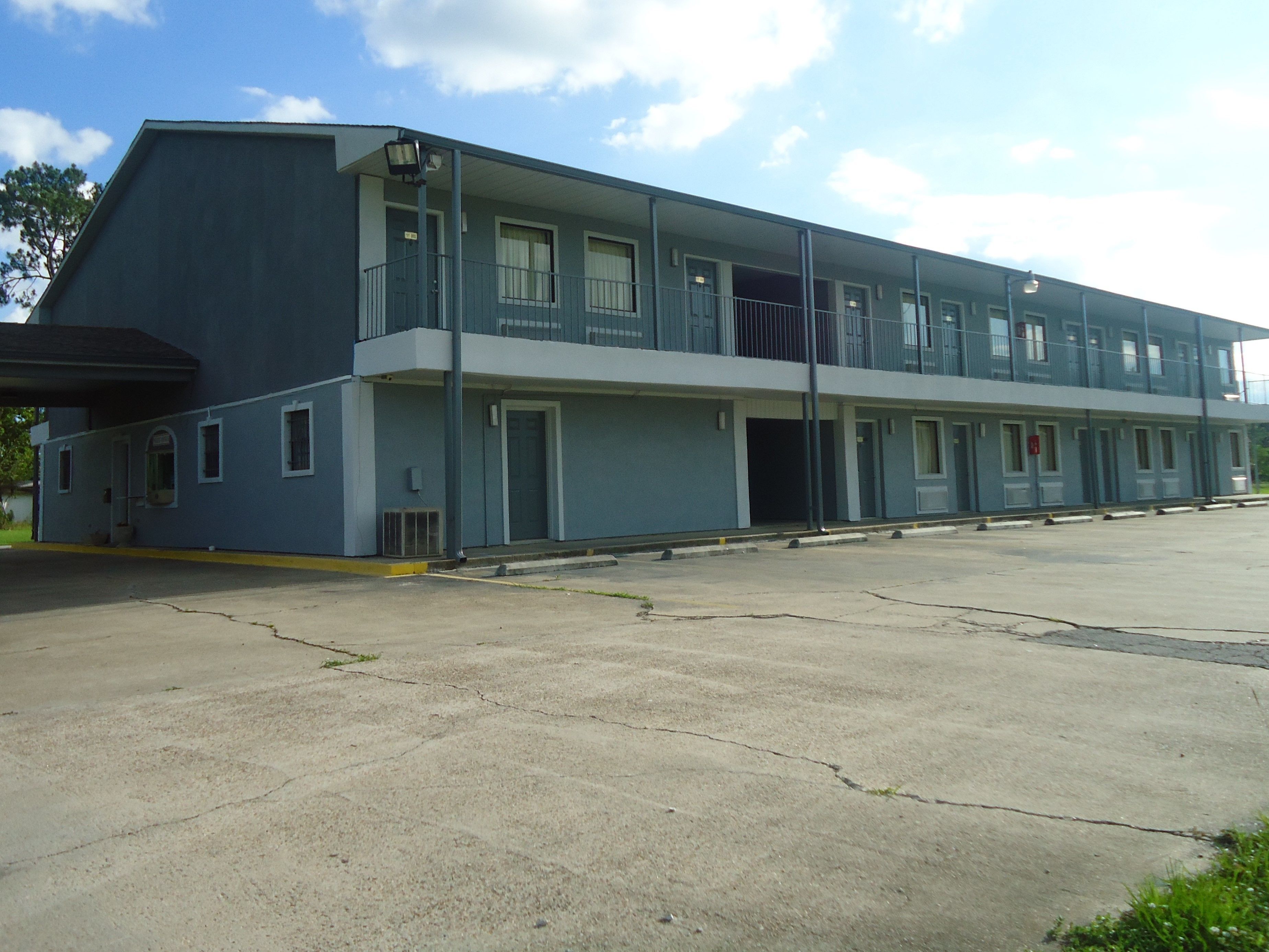 A two-story motel with a flat roof, multiple windows, and a parking lot.