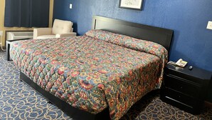 A hotel room with a bed, a chair, a dresser, and a framed picture on the wall. - Super 6 Inn (Carencro)