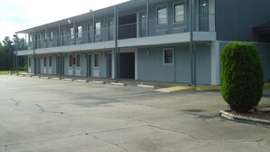A multi-story motel with a flat facade, balconies, and a parking lot. - Super 6 Inn (Carencro)