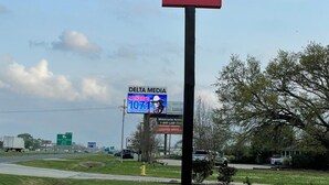 A Super 6 Inn sign with a clear view of the surrounding area including a Delta Media billboard and a grassy landscape. - Super 6 Inn (Carencro)