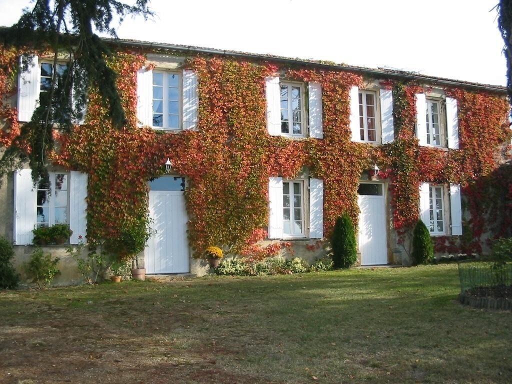 A two-story building with white shutters and a garden in front.