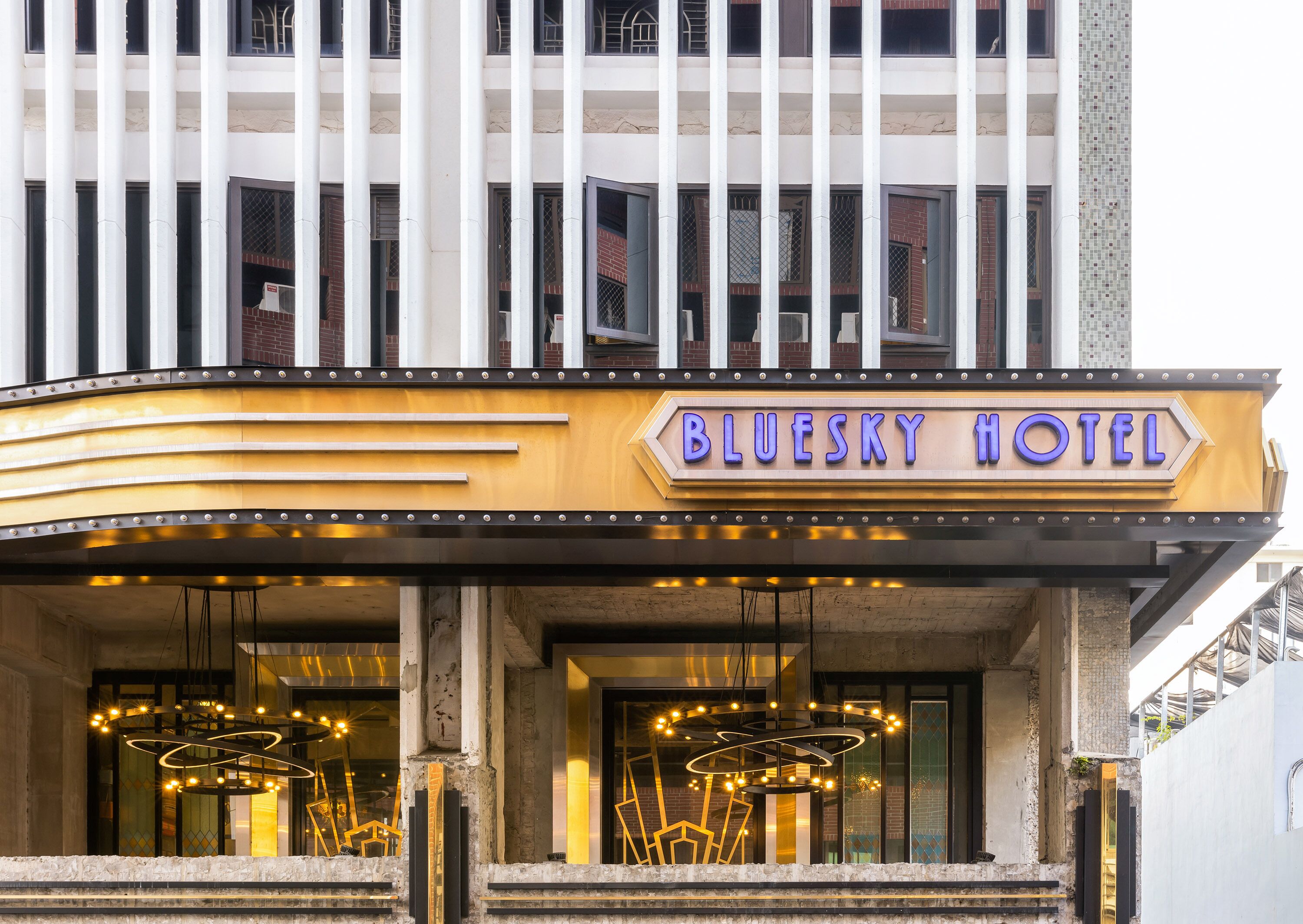The Bluesky Hotel entrance with a marquee sign, large windows, and a modern light fixture.