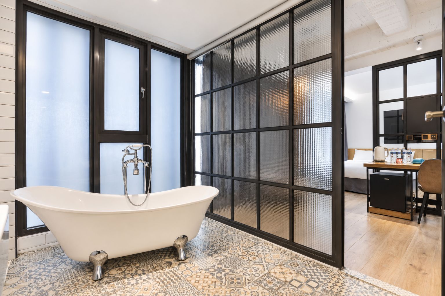 A modern bathroom with a freestanding bathtub, a shower, and a large window with frosted glass panels.