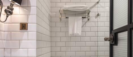 A bathroom with a white toilet, a sink with a black towel holder, patterned floor tiles, and a glass shower door.