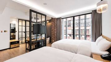 Une chambre d’hôtel avec deux lits, un bureau, une télévision et une grande fenêtre donnant sur la ville.