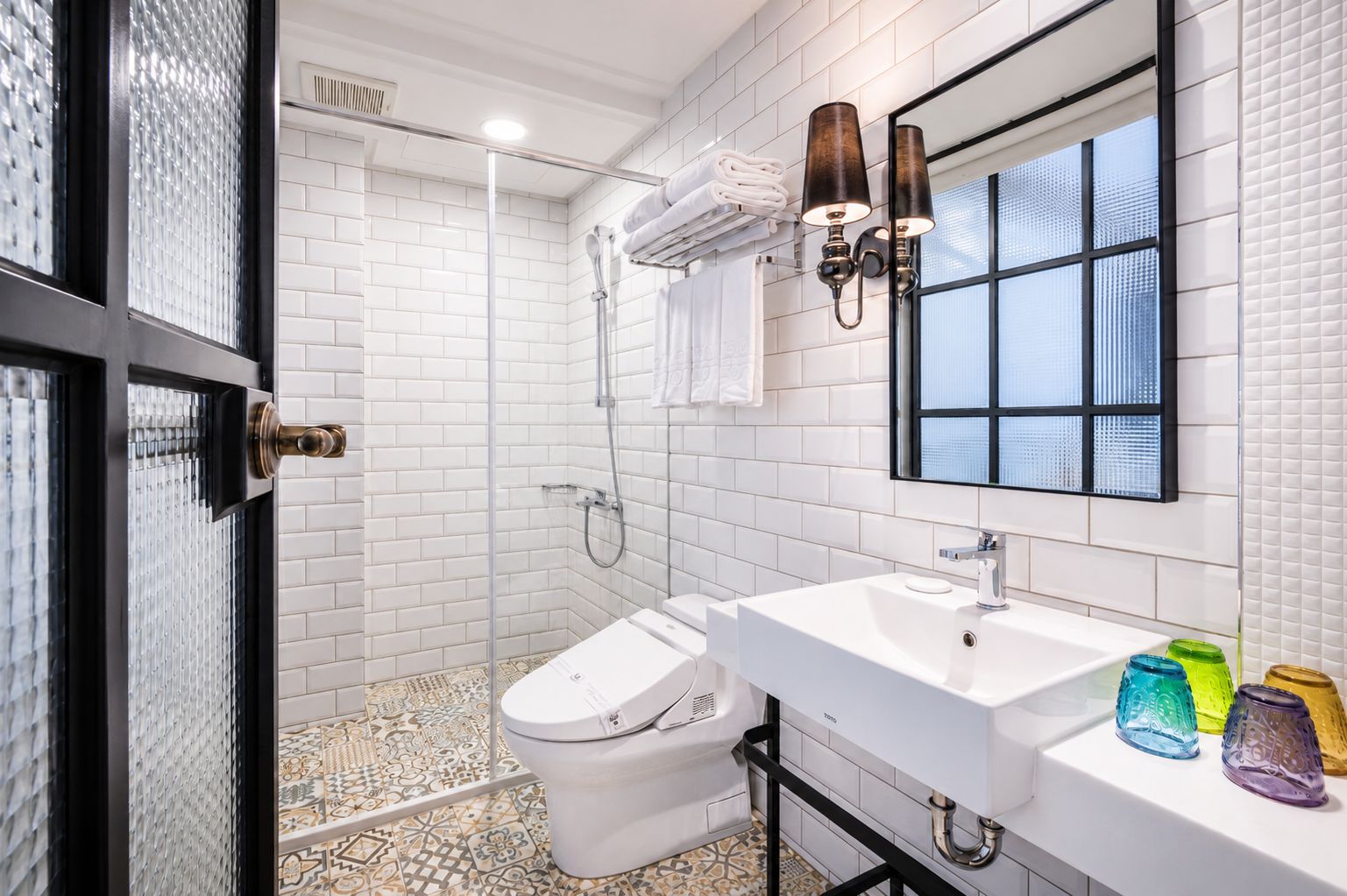 Un bagno moderno con doccia rivestita in piastrelle bianche, un water, un lavandino e uno specchio.