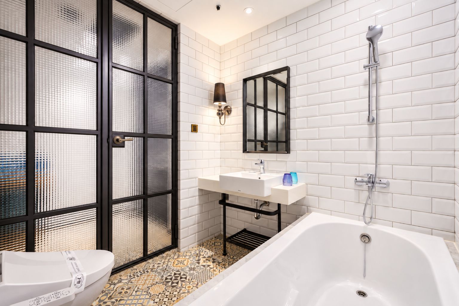 A modern bathroom with a white bathtub, a glass-enclosed shower, and a white sink with a mirror above it.