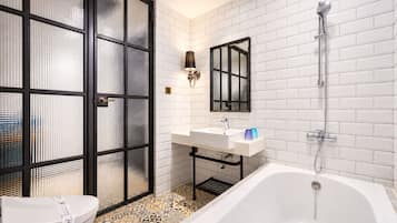 A modern bathroom with a white bathtub, a glass-enclosed shower, and a white sink with a mirror above it.