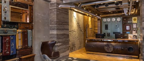 A lobby with vintage suitcases stacked against the wall, a modern reception desk, and a geometric patterned floor.