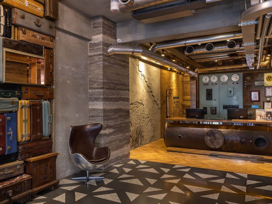 A lobby with vintage suitcases stacked against the wall, a modern reception desk, and a geometric patterned floor.