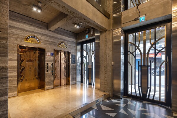 An interior with three elevator doors, a marble floor, and a view of the street through a glass door. - BlueSky Hotel (Taichung)