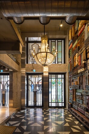 A lobby with a chandelier, patterned floor, and a wall of suitcases. - BlueSky Hotel (Taichung)