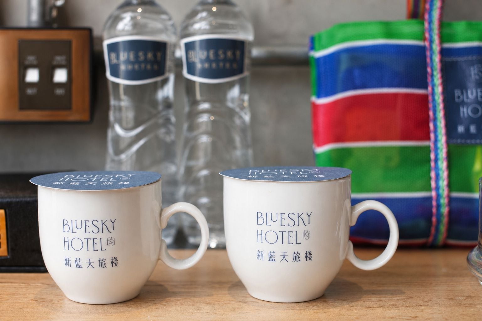 Two white mugs with 'Bluesky Hotel' branding on a wooden surface.