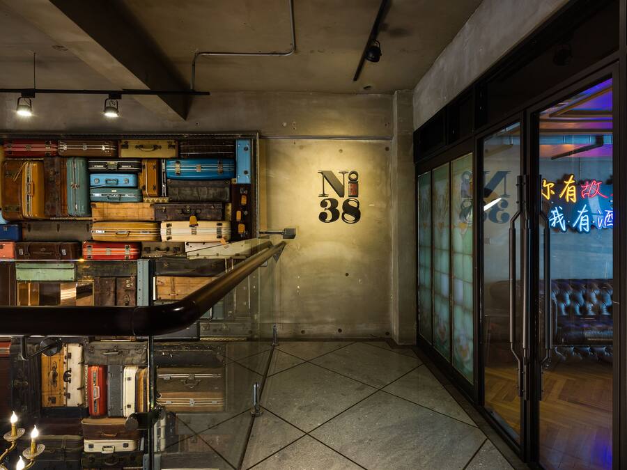 Een kamer met een muur waarop koffers staan en een bord met daarop '38'.