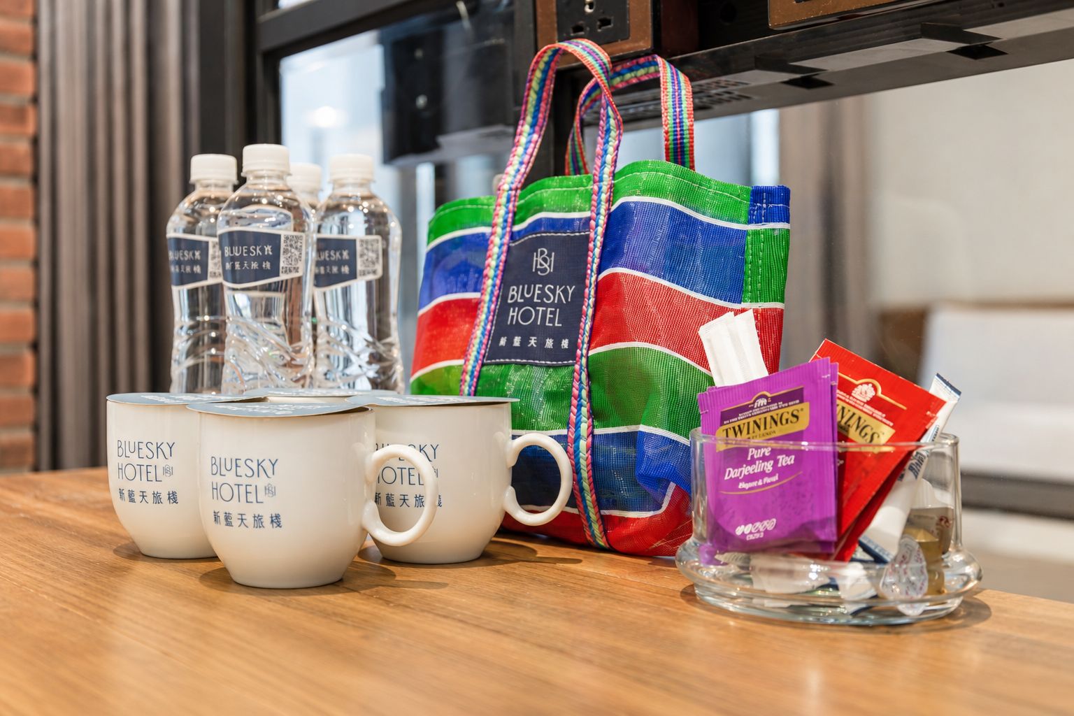 A table with water bottles, a colorful tote bag, a mug, and tea packets.