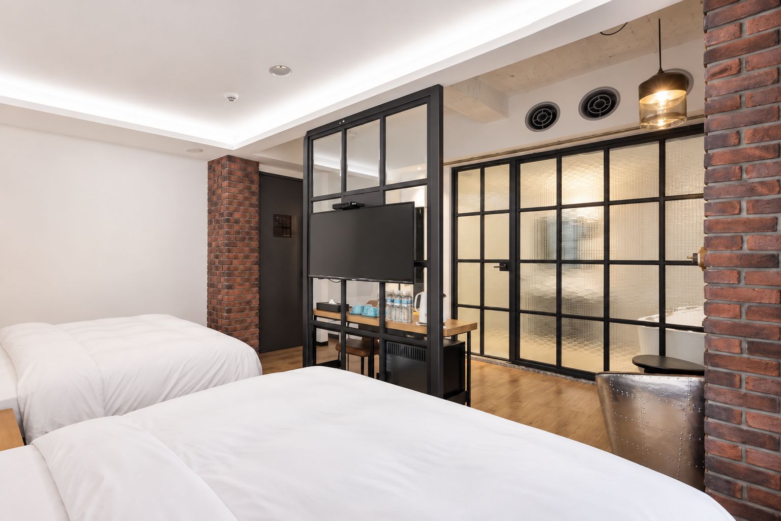 Une chambre d’hôtel avec deux lits, une télévision, un bureau avec une chaise et une grande fenêtre donnant sur un beau paysage.