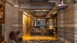 Un hall con mostrador de recepción, una silla moderna y un piso estampado.
