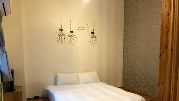 Cama bem arrumada com roupa de cama branca em quarto com piso de madeira e parede lisa.
