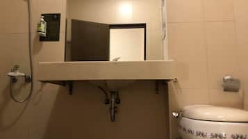 Un baño con lavamanos, espejo, ducha e inodoro.