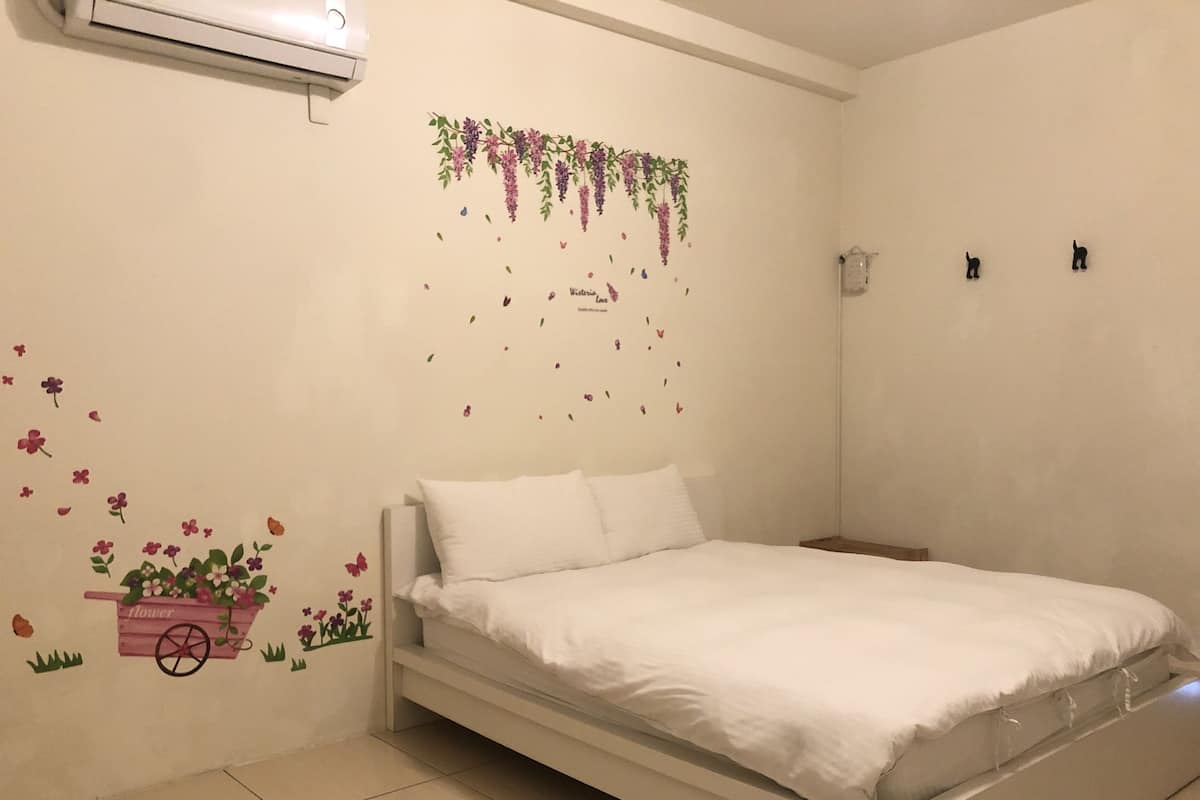 Une chambre à coucher avec un lit, un climatiseur fixé au mur et des autocollants décoratifs sur les murs.