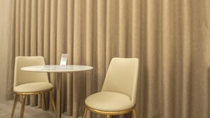 A modern room with two chairs and a small round table, featuring a vertical striped curtain backdrop. - 168 Motel-Taoyuan (Taoyuan City)
