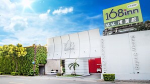 A modern building with a prominent '168inn' sign, a red entrance door, and a green lawn with a palm tree. - 168 Motel-Taoyuan (Taoyuan City)