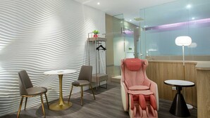 A modern room with a unique wavy wall design, a massage chair, two chairs, a small table, and a lamp. - 168 Motel-Taoyuan (Taoyuan City)